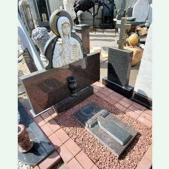 Горизонтальный памятник из диаббаза с барельефом святой из мрамора на узкой подставке с надгробной плитой с резным составным крестом